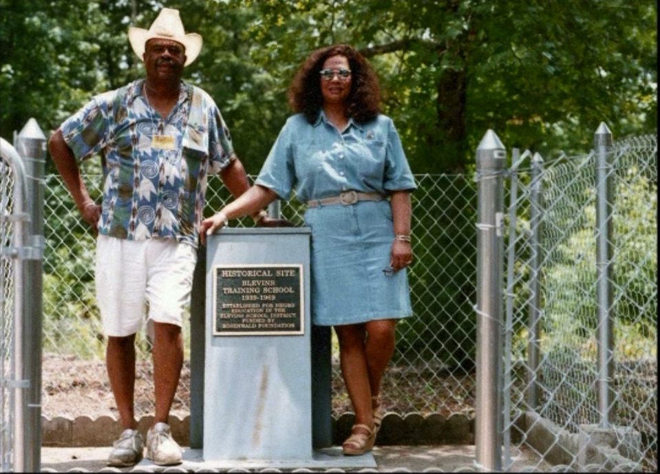 Two alumni stand on either side of the Blevins Training School historical marker during the 1999 reunion.