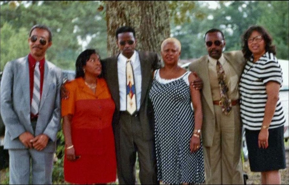 Six alumni dressed for the occasion pose together beneath a large tree during the 1999 reunion.